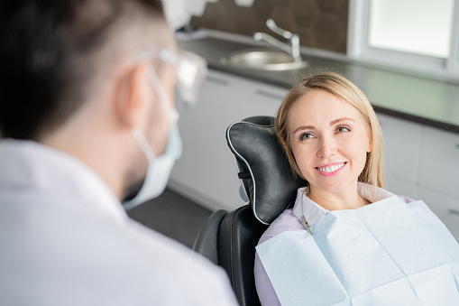 female patient smiling at her doctor while sitting in a patient chair
