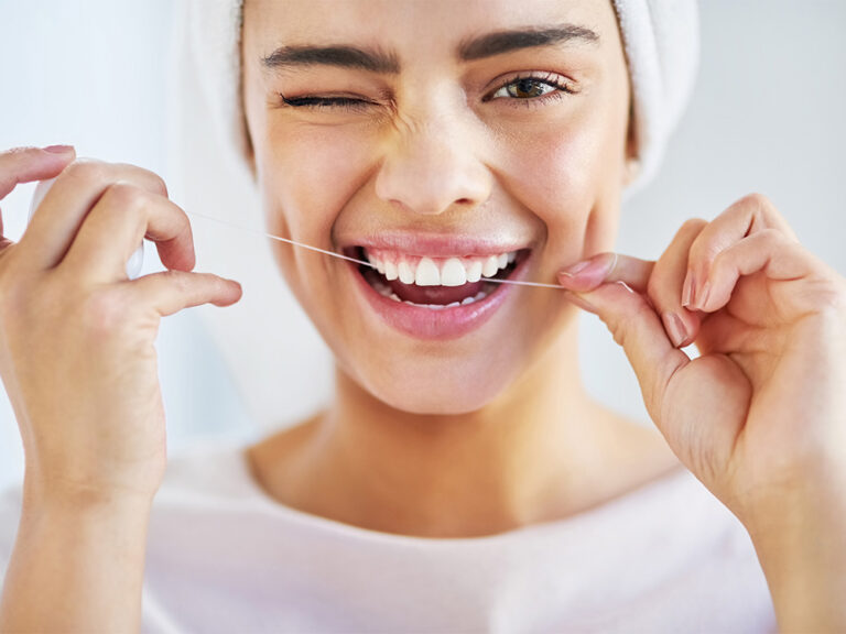 The image shows a person flossing their teeth, emphasizing oral hygiene.